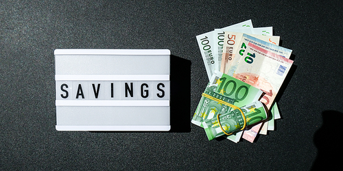 Lightbox board with word SAVINGS in black letters around Euro banknotes. Money, Business, finance, investment, saving. Cash bill. Business budget of wealth and prosperity finance