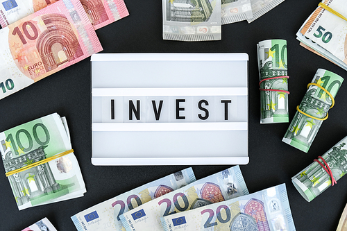 Lightbox board with word INVEST in black letters around euro banknotes. Money, Business, finance, investment, saving. Cash bill. Business budget of wealth and prosperity finance. Passive income