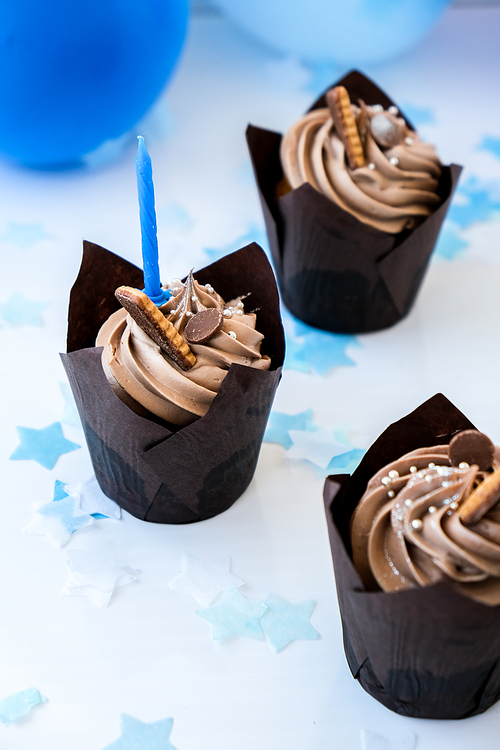Delicious chocolate cupcakes with cream and candle. Three chocolate muffin. Birthday cake party. Boy or girl baby party cake Homemade Chocolate Cupcake