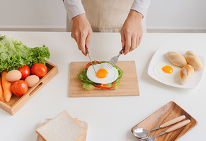 Hands of man prepare breakfast with sandwich with poached eggs