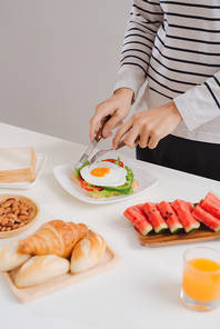Hands of man cut the eggs on paper, served with bread, herbs, sausage and fresh juice.