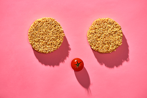 Food concept. Face made of Dry noodle and tomato on pink background