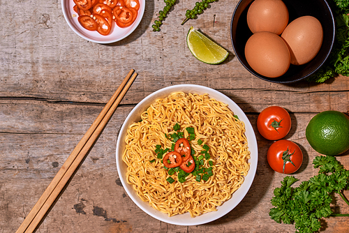 noodle in bowl and ingredients on wood background top view