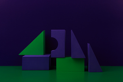 Duotone geometric composition with green and purple figures on green table against purple background