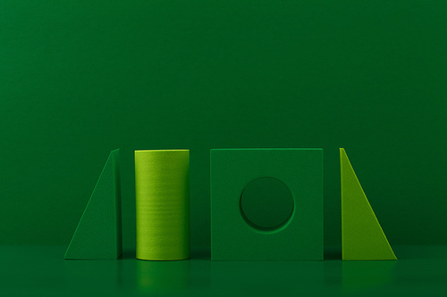 Simple monochromatic still life with light and dark green geometric figures on green background with space for text