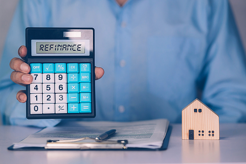 Hands of business man holding calculator for calculate refinance home and expense for loan mortgage, investment and banking, property and finance, real estate and transfer for debt with refinance.