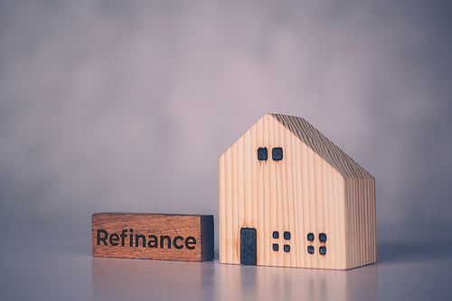 Wooden block with refinance word and house model about home and finance, loan and mortgage for real estate and property, residential and planning with budget, investment and earning, business concept.