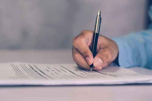 Hands of businessman signing contract about agreement for success on desk in the office, man signature document paperwork with pen, legal insurance and decision for deal, business concept.