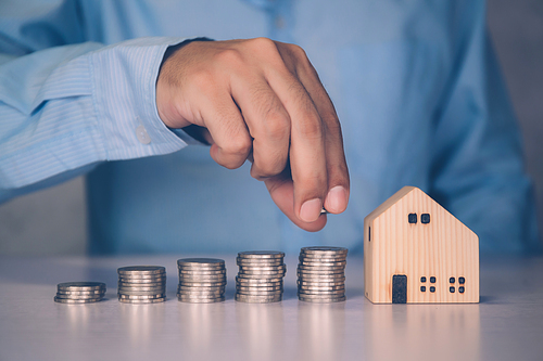 Hands of businessman and stack of coin with saving money for real estate and success, finance and investment, insurance home, deposit and property, residential and financial, business concept.