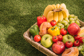 Fresh healthy tropical fruit on a picnic blanket on the grass with grapes, apple, grapefruit, orange and banana