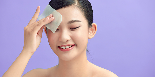 Woman using facial oil blotting paper, beauty product at studio