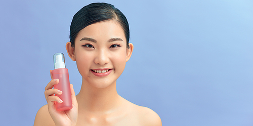 Smiling young girl demonstrates moisturizing tonic in pink bottle.