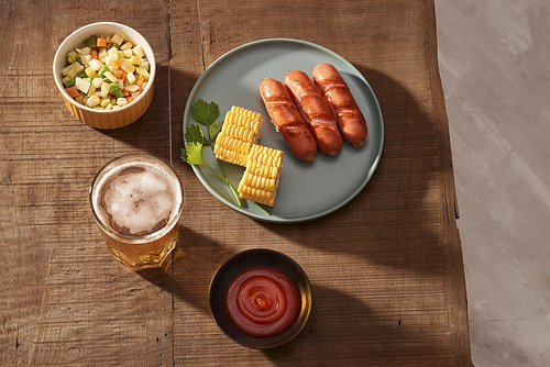 Home grilled sausages on a dark plate, a meat dish on a dark wooden background, hot sausages with spices and salt in a home kitchen, copy space, rustic style, art