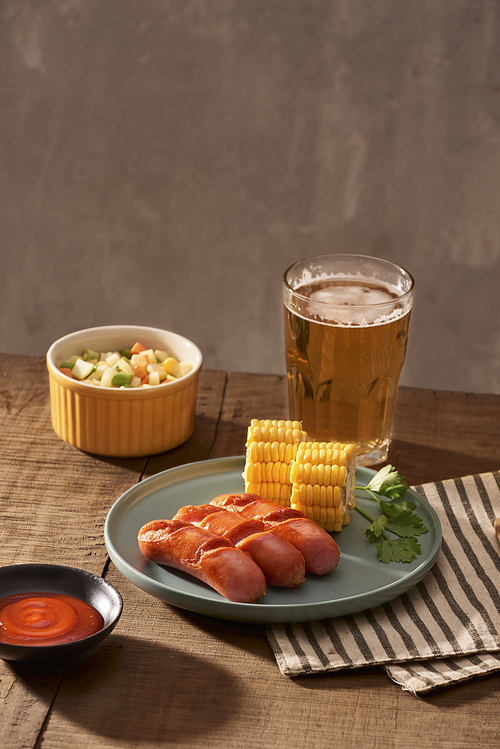 Home grilled sausages on a dark plate, a meat dish on a dark wooden background, hot sausages with spices and salt in a home kitchen, copy space, rustic style, art