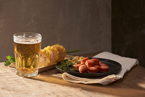 Grilled sausages with glass of beer on wooden table with copy space.