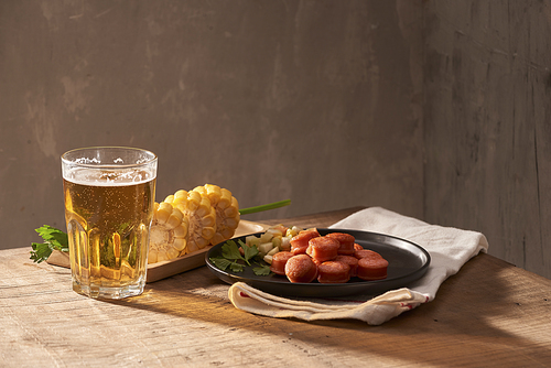 Grilled sausages with glass of beer on wooden table with copy space.