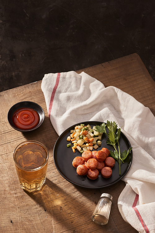 Beer and grilled sausages on wooden background