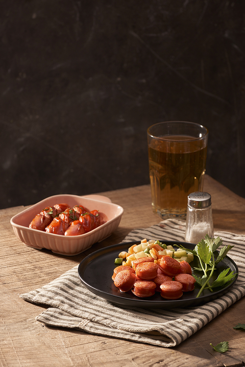 Glass of delicious beer with grilled sausages on wooden table