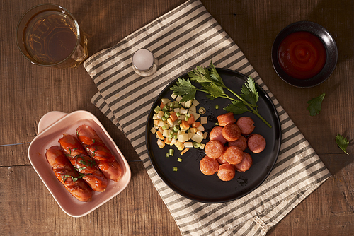 Glass of delicious beer with grilled sausages on wooden table