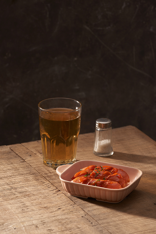 Glass of delicious beer with grilled sausages on wooden table