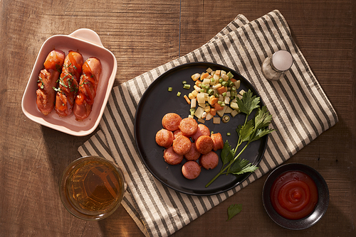 Glass of delicious beer with grilled sausages on wooden table