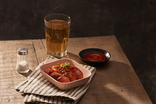 Glass of delicious beer with grilled sausages on wooden table