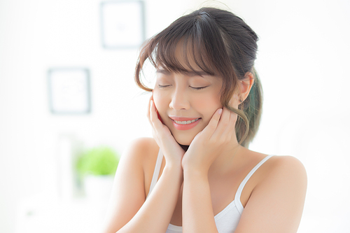 Portrait of beautiful young asian woman smile while wake up healthy and wellness with sunrise at morning in the bedroom, asia girl skin care with happy with fresh, lifestyle and relax concept.