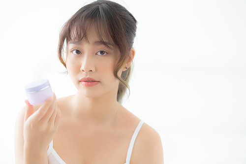 Beautiful portrait young asian woman holding and presenting cream or lotion product, beauty asia girl show cosmetic makeup and moisturizing for skin care, healthy care and wellness concept.