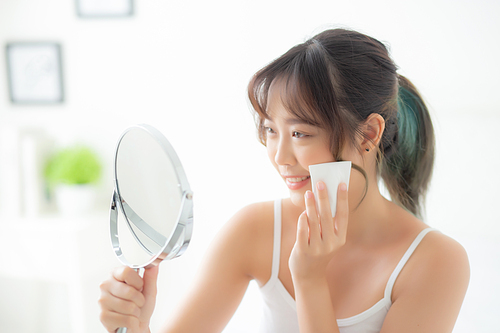 Beautiful portrait young asian woman smile and joy with skin care use oil blotting paper on face looking mirror in the room, beauty asia girl happy and cheer makeup and cosmetic, health care on facial concept.