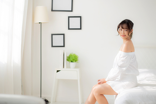 Portrait of beautiful young asian woman sitting looking the window and smile while wake up with sunrise at morning, beauty asia girl happy with freshness and cheerful, lifestyle and relax concept.