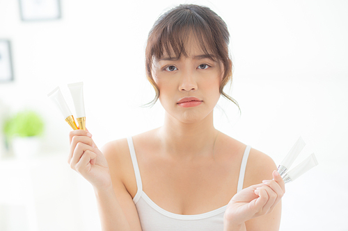 Beautiful portrait young asian woman holding and presenting cream or lotion product, beauty asia girl show cosmetic makeup and moisturizing for skin care, healthy care and wellness concept.