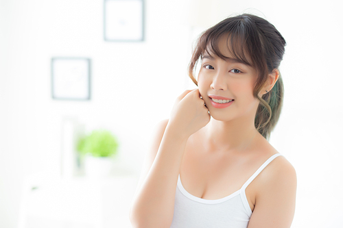 Portrait of beautiful young asian woman smile while wake up healthy and wellness with sunrise at morning in the bedroom, asia girl skin care with happy with fresh, lifestyle and relax concept.