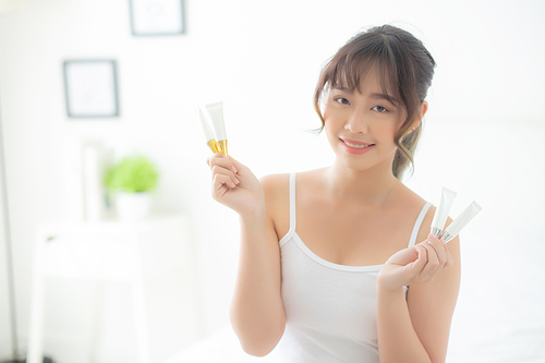 Beautiful portrait young asian woman holding and presenting cream or lotion product, beauty asia girl show cosmetic makeup and moisturizing for skin care, healthy care and wellness concept.