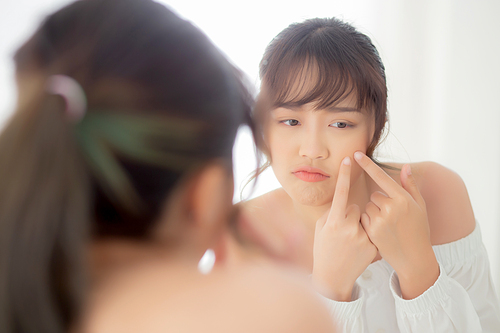 Portrait beautiful young asian woman looking the mirror is a acne, zit treatment, girl problem beauty face, perfect with wellness in the bedroom at home with skin care and  healthcare concept.