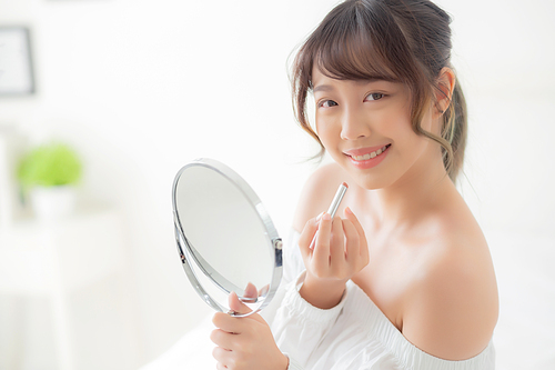 Beautiful portrait young asian woman looking mirror applying makeup lipstick at room, beauty lips asia girl makeup and cosmetic fashion on mouth at home, lifestyle and health care concept.