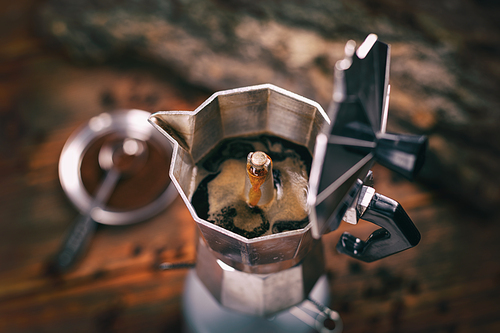Italian traditional coffee maker with hot coffee flowing out from the spout