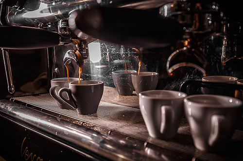 Coffee machine preparing fresh coffee and pouring into white cups at restaurant, bar or pub