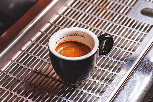 Cup of espresso coffee on steel coffee machine tray