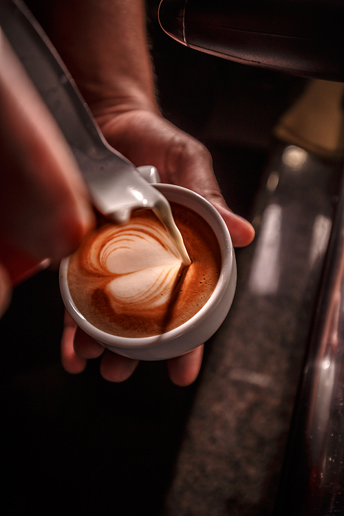 Barista pouring milk for prepare cup of coffee, latte art, Coffee preparation and service concept