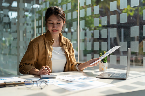 Close up accountant woman using calculator and laptop for do math finance on wooden desk in office and business working background, tax, accounting, statistics and analytic research concept.