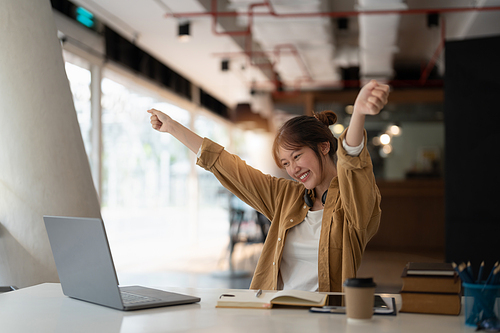 Happy young asian student hands up with excitement during home distance education.