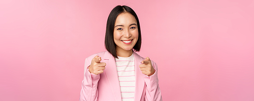 Its you, congrats. Smiling enthusiastic korean corporate lady, businesswoman pointing fingers at camera congratulating, praising you, standing over pink background.