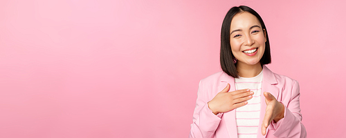 Portrait of smiling, pleasant businesswoman shaking hands with business partner, handshake, extending hand and saying hello, standing over pink background.