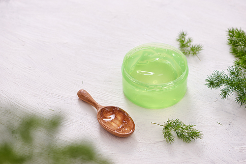 cosmetic creams with leaves on white wooden table background