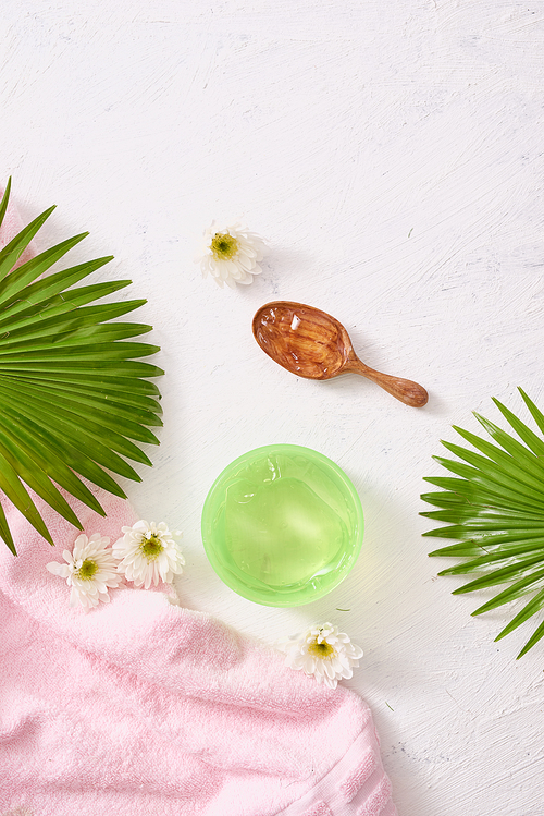 cosmetic creams with leaves on white wooden table background