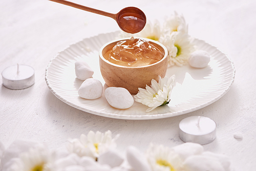 Aloe vera gel on a bowl, with chrysanthemum and candle in stone table