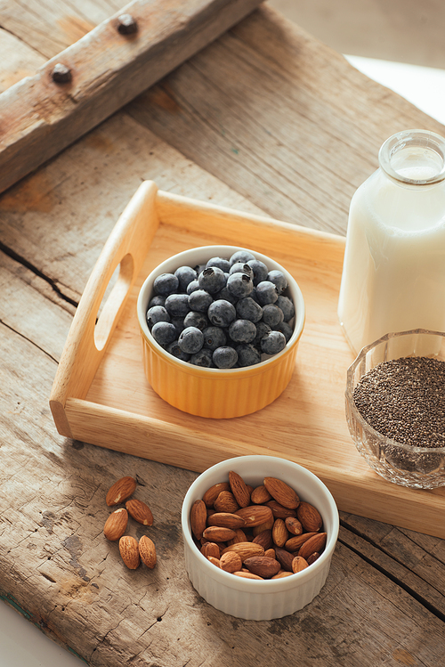 Healthy vegan breakfast. Bottled milk with chia, almond, fresh fruit and berries over wooden table background, copy space. Clean eating, weight loss, vegetarian, raw food concept