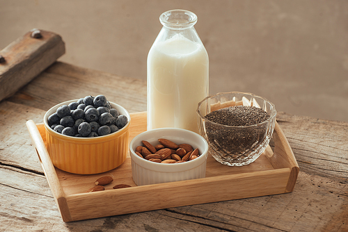 Healthy vegan breakfast. Bottled milk with chia, almond, fresh fruit and berries over wooden table background, copy space. Clean eating, weight loss, vegetarian, raw food concept