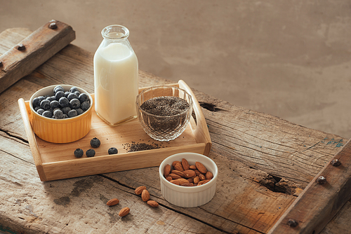 Healthy vegan breakfast. Bottled milk with chia, almond, fresh fruit and berries over wooden table background, copy space. Clean eating, weight loss, vegetarian, raw food concept