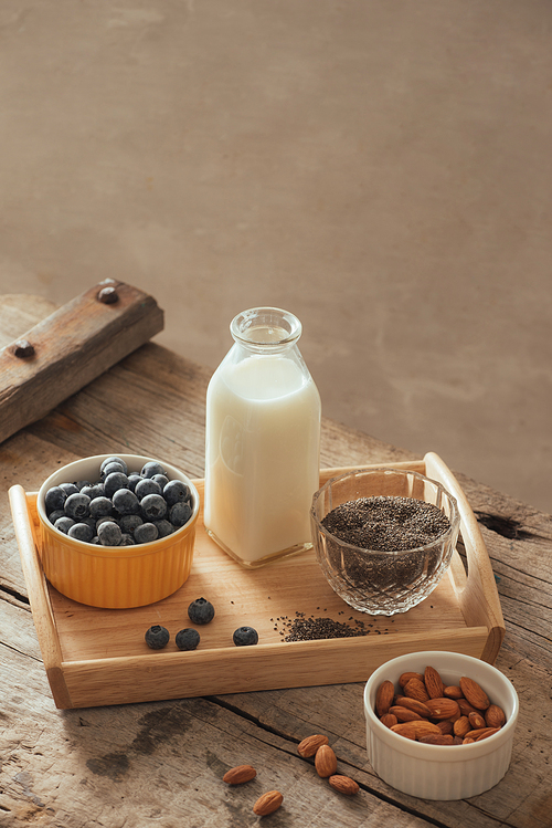 Healthy vegan breakfast. Bottled milk with chia, almond, fresh fruit and berries over wooden table background, copy space. Clean eating, weight loss, vegetarian, raw food concept